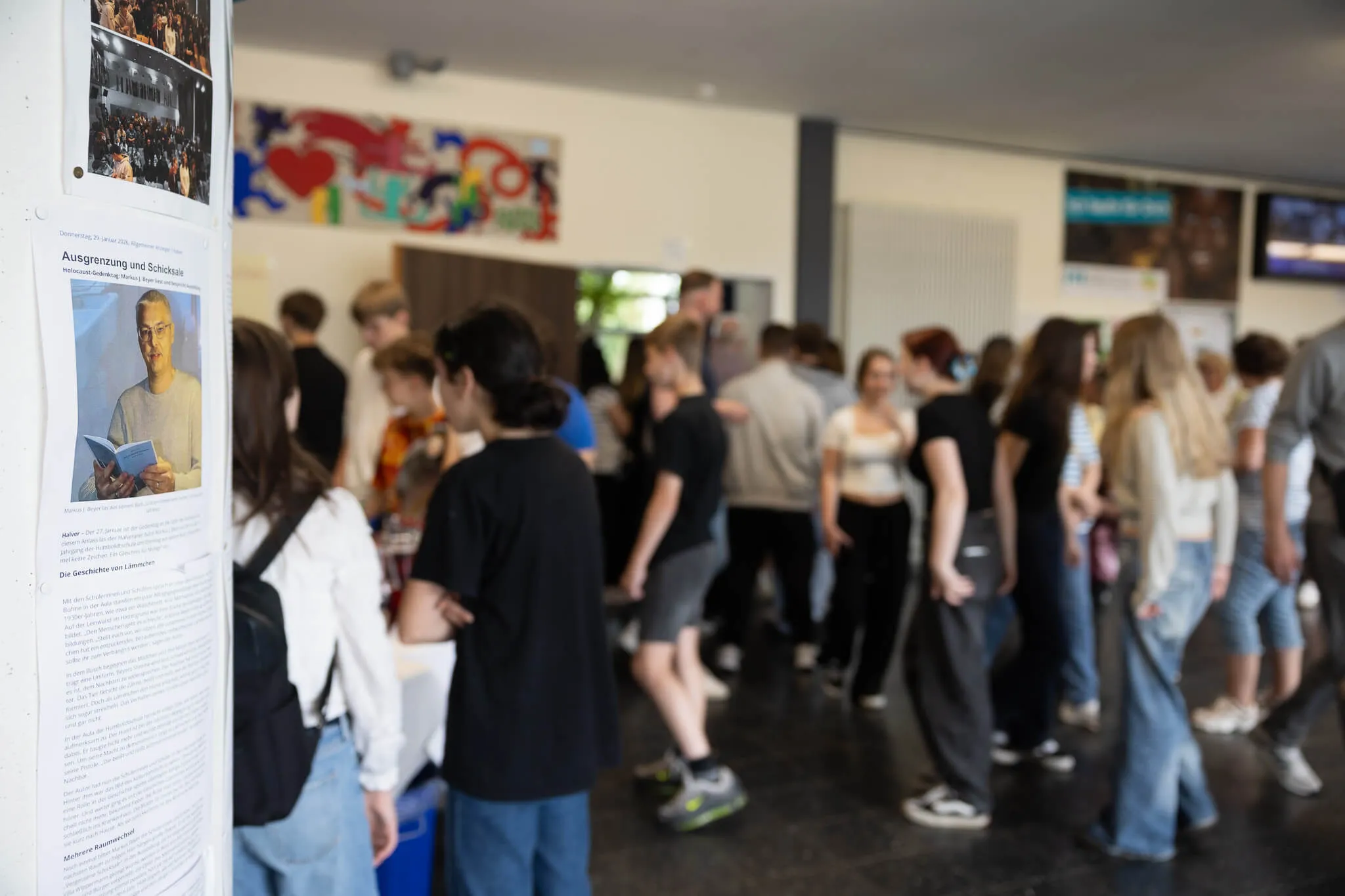 Schüler betrachten Fotos und Texte an einer Pinnwand während eines Schulfests in der Humboldtschule.