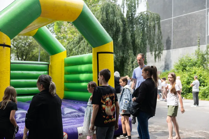 Eine Hüpfburg steht im Vordergrund, umgeben von Kindern und erwachsenen Besuchern des Schulfests der Humboldtschule.