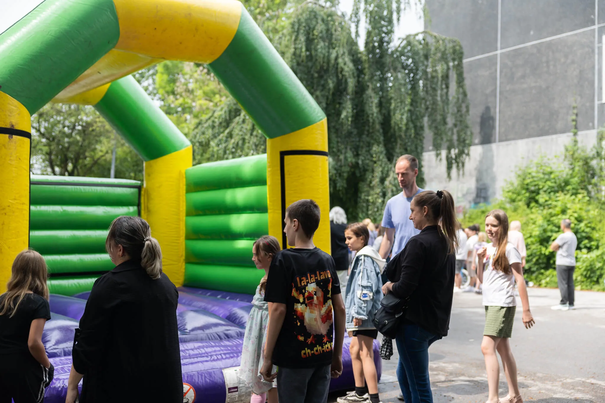 Eine Hüpfburg steht im Vordergrund, umgeben von Kindern und erwachsenen Besuchern des Schulfests der Humboldtschule.