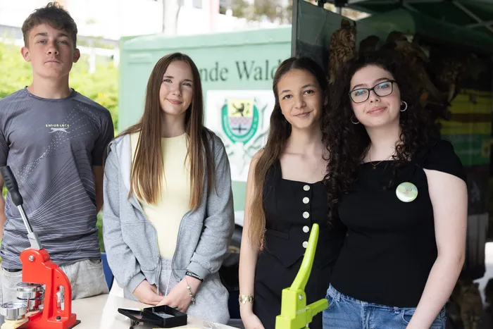 Vier Jugendliche stehen vor einem Fahrzeug mit dem Aufdruck „Freunde Wald“. Sie halten Modelle und Werkzeuge in den Händen.