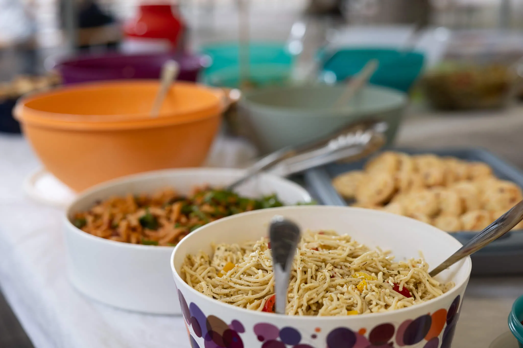 Verschiedene Schüsseln mit Nudelsalat, Gemüse und Snacks stehen auf einem Tisch bereit, vermutlich als Buffet für ein Schulfest.