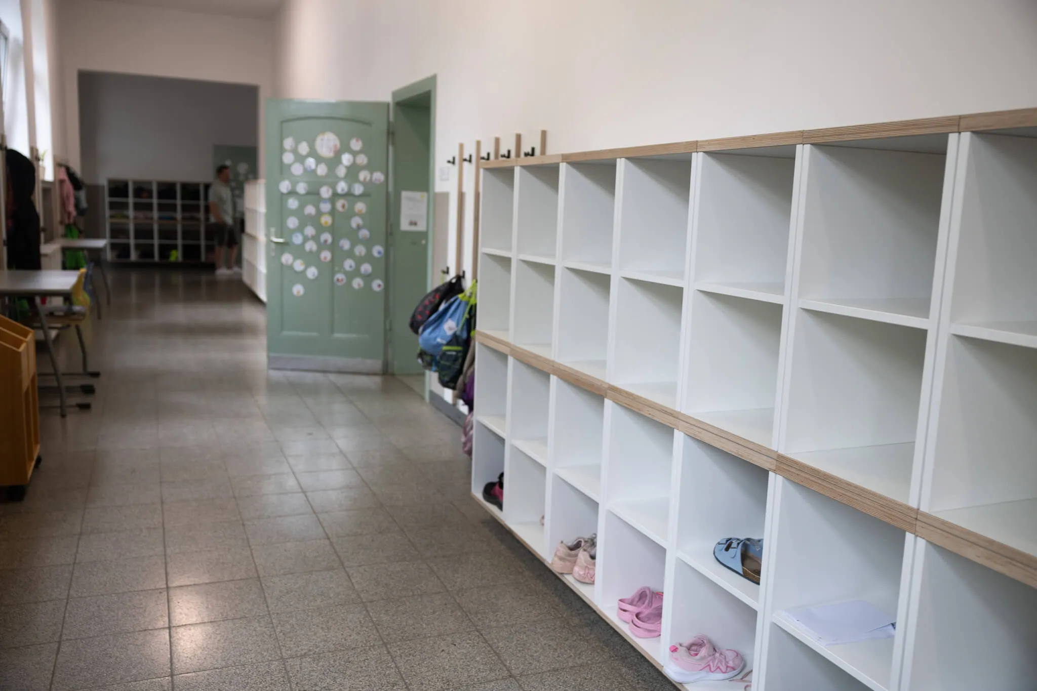 Leere Fächer an einer Wand in einem Flur der Lindenhofschule, einige Schultaschen und Schuhe darunter.