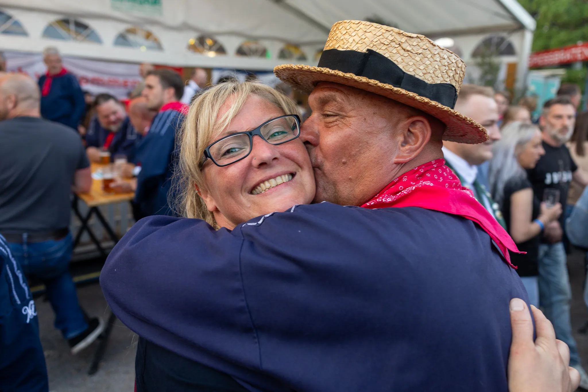 Ein Paar umarmt sich herzlich auf dem Königsball der Bauernschützen im Festzelt. Die Frau lacht, während der Mann sie auf die Wange küsst.