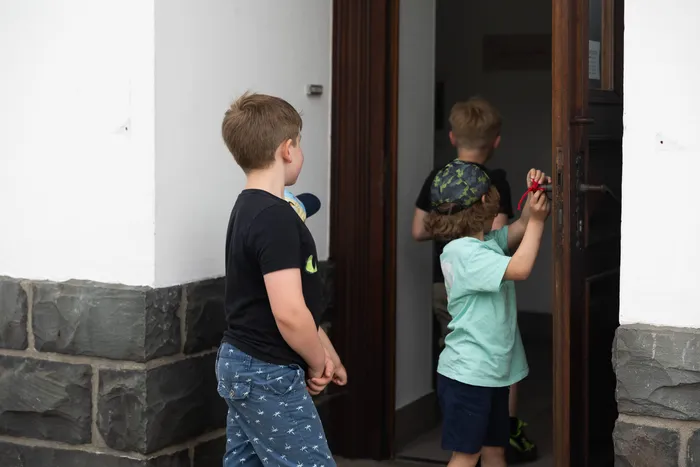 Mehrere Kinder betreten eine Bücherei, ein Junge öffnet die Tür von innen.
