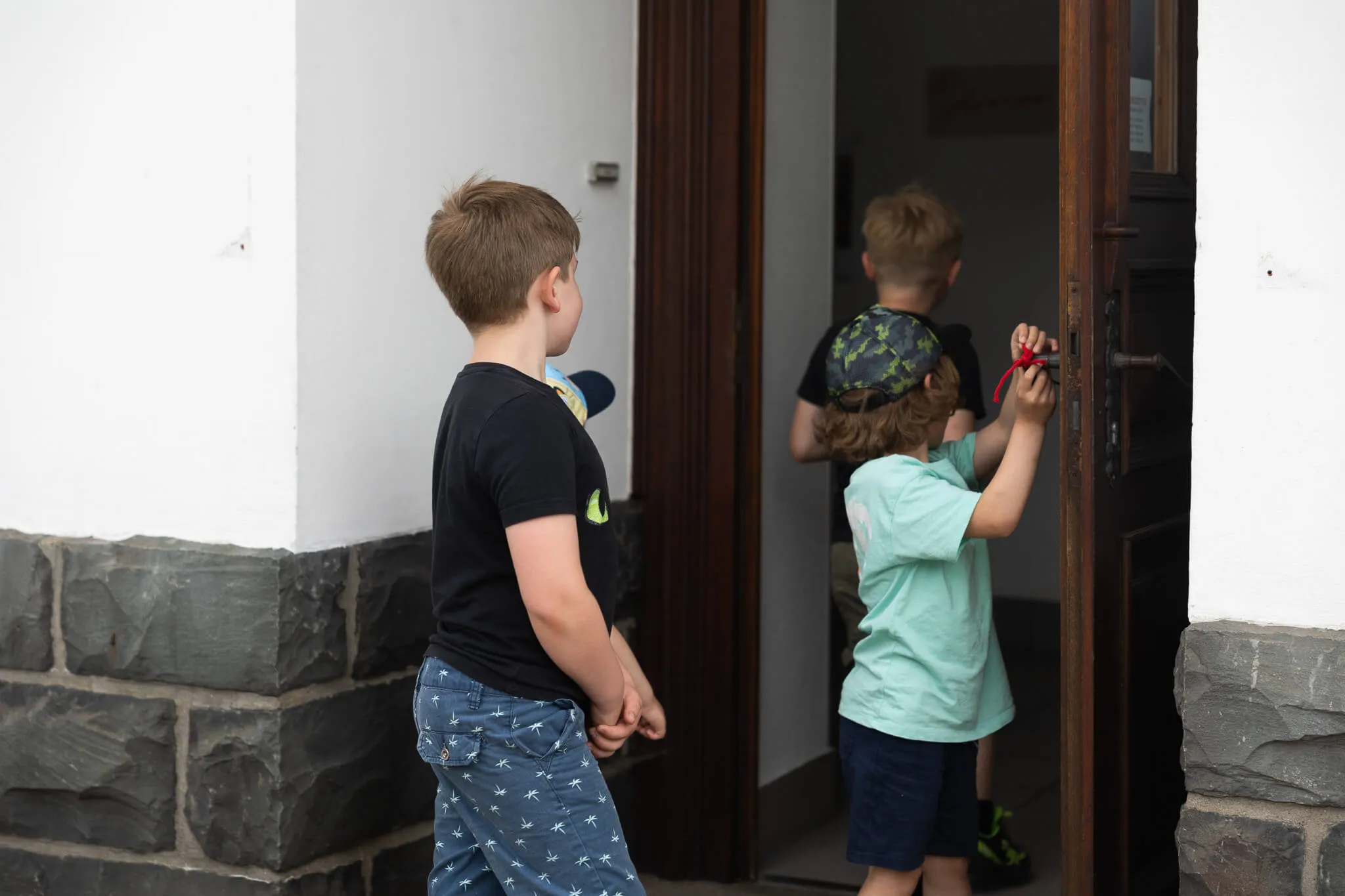 Mehrere Kinder betreten eine Bücherei, ein Junge öffnet die Tür von innen.
