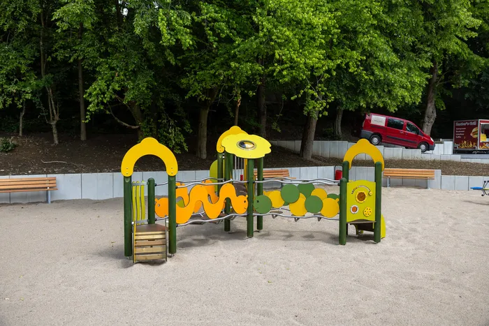 Bunter Spielplatz mit Klettergerüst und Rutsche auf einem Sandplatz neben dem Familienbad Nattenberg.