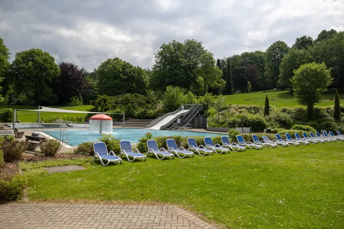 Freibad Nattenberg mit Schwimmbecken, Rutsche und Liegestühlen auf einer Rasenfläche, umgeben von Bäumen.