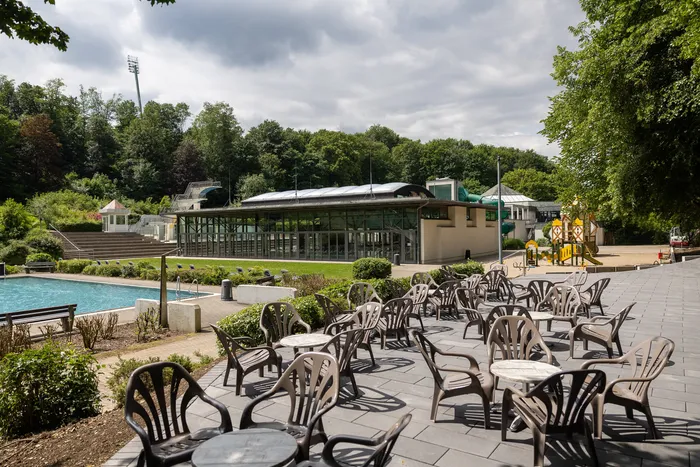 Freiluftbad Nattenberg mit Schwimmbecken, Liegewiese, Restaurantbereich mit Tischen und Stühlen sowie Kinderspielplatz.