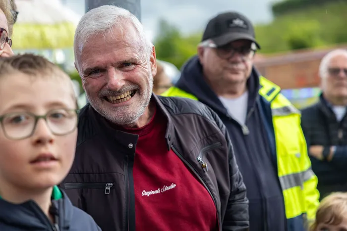 Bürgermeister Armin Kibbert lächelt in die Kamera, während er bei der Eröffnung der Kirmes ein Bierfass ansticht. Im Hintergrund sind weitere Menschen zu sehen.