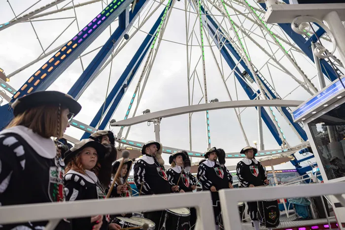 Eine Blaskapelle in traditioneller Tracht spielt vor einem großen Riesenrad auf der Kirmes in Halver.