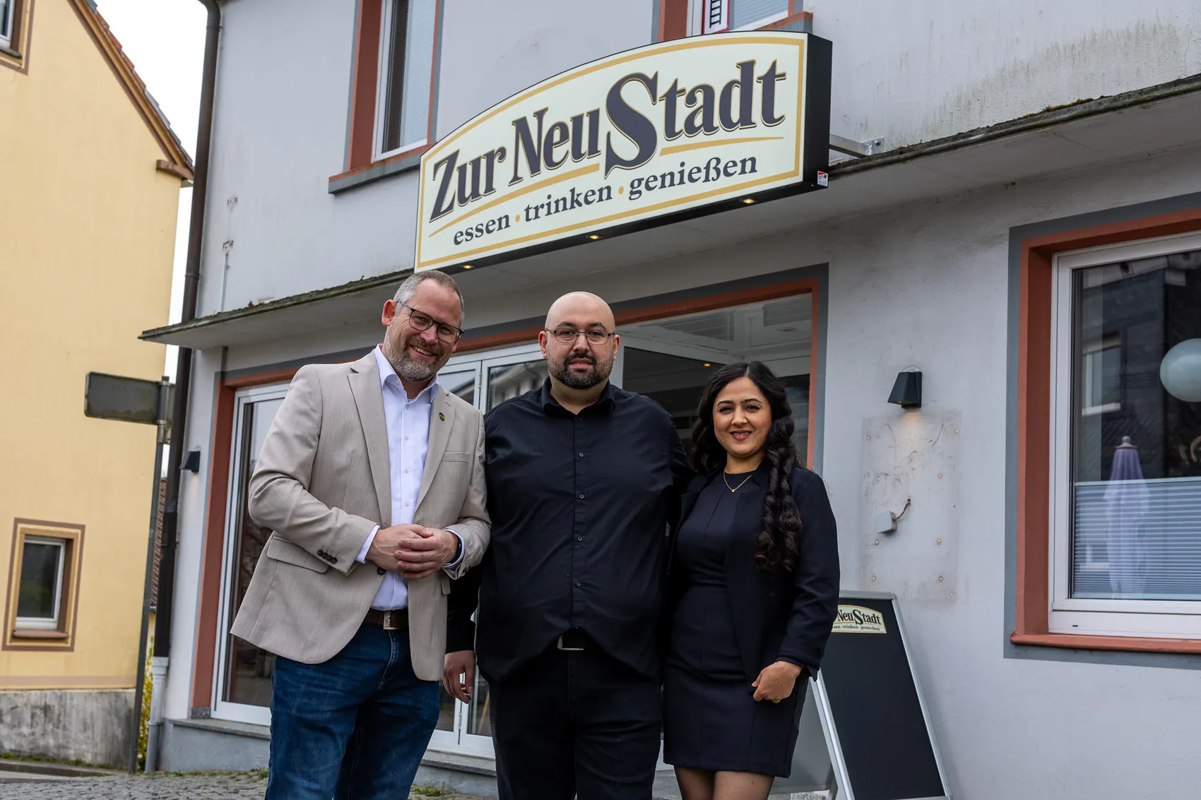 Emrah Saygili steht vor seinem Restaurant „Zur Neustadt“ mit seiner Frau Bedriye Saygili und Bürgermeister Armin Kibbert.