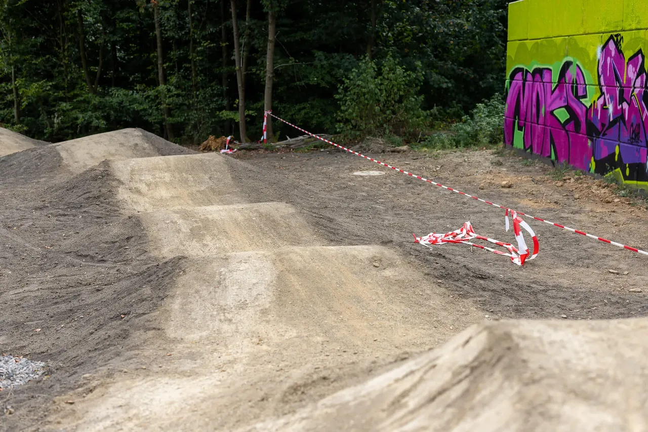 Erdhügel einer Dirt-Strecke im neuen Bikepark in Halver, markiert durch rot-weißes Absperrband.