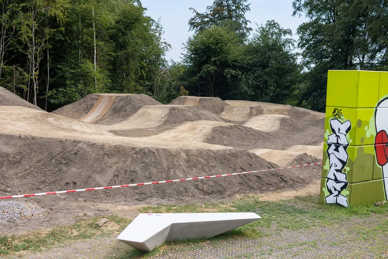 Aufgeschüttete Erdhügel und Fahrspuren für den neuen Bikepark in Halver vor einem Waldrand.