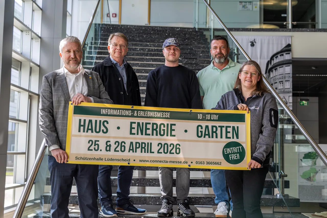 Fünf Personen stehen vor einem Banner mit der Aufschrift „Haus · Energie · Garten“ und dem Datum 25. & 26. April 2026. Im Hintergrund eine moderne Glasfassade.