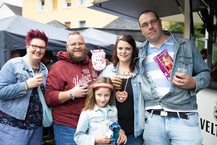 Familie mit Kind posiert lächelnd auf der Halveraner Kirmes, jeder hält ein Glas Bier oder Schorle in der Hand.