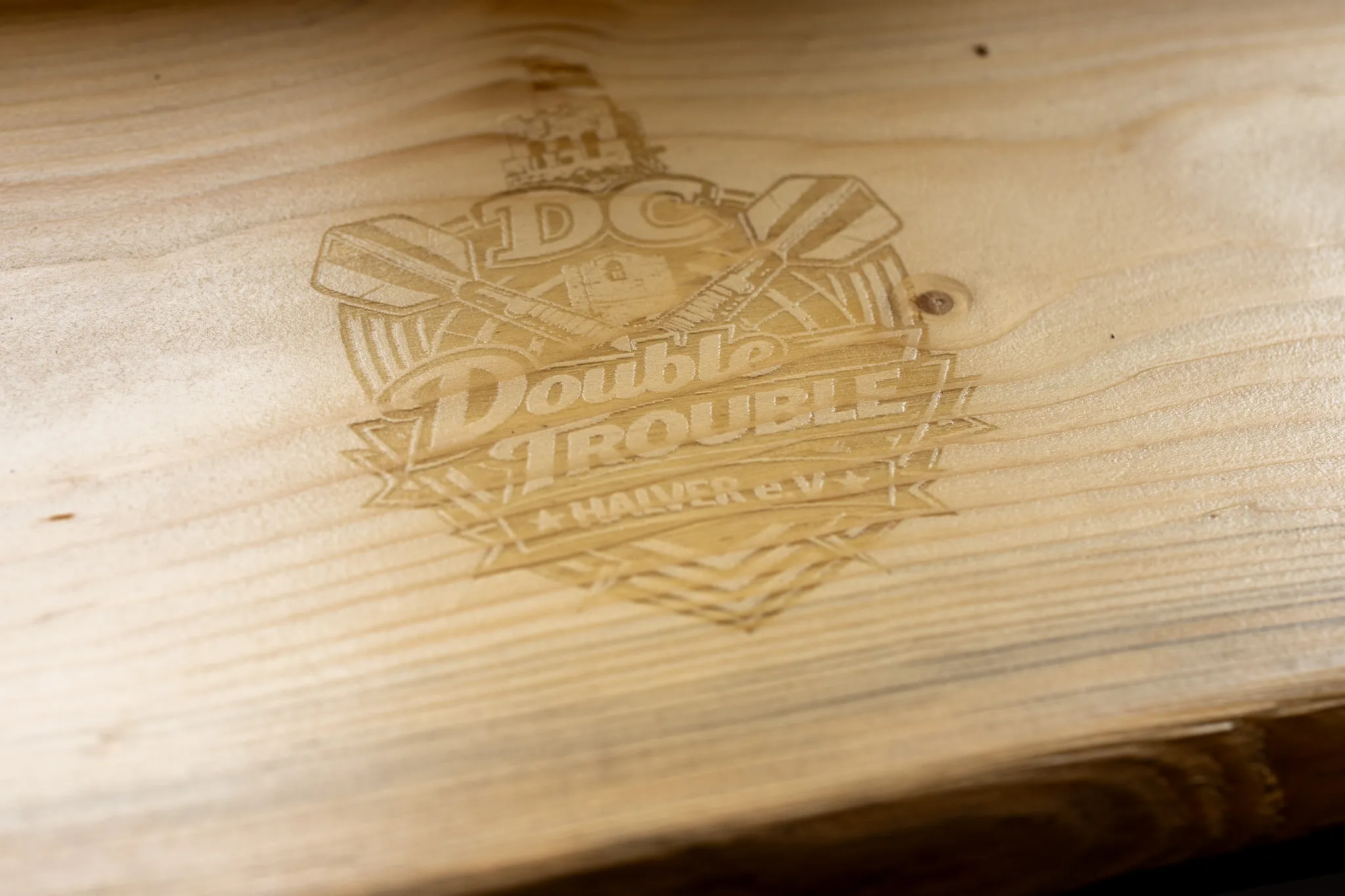 Holzfensterbank mit eingraviertem Logo des Vereins „Double Trouble Halver e.V.“, das stilisierte Elemente wie ein Wappen und eine Windmühle zeigt.