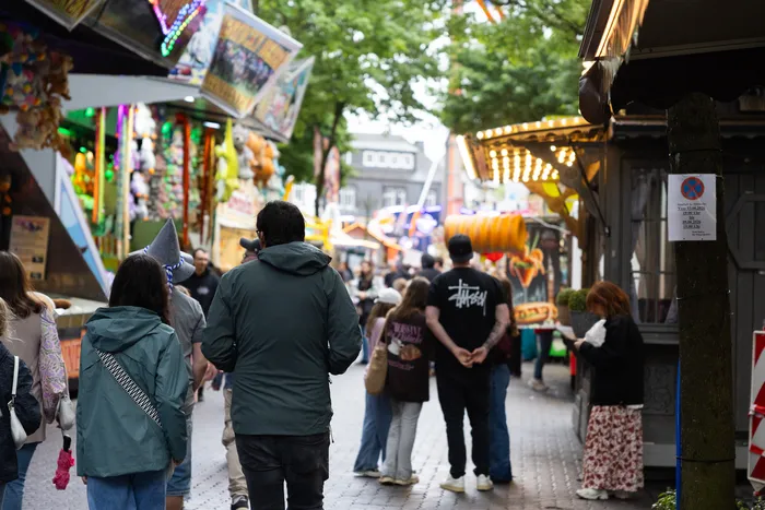 Menschenmenge auf der Halveraner Kirmes, im Hintergrund bunt beleuchtete Fahrgeschäfte und Buden.