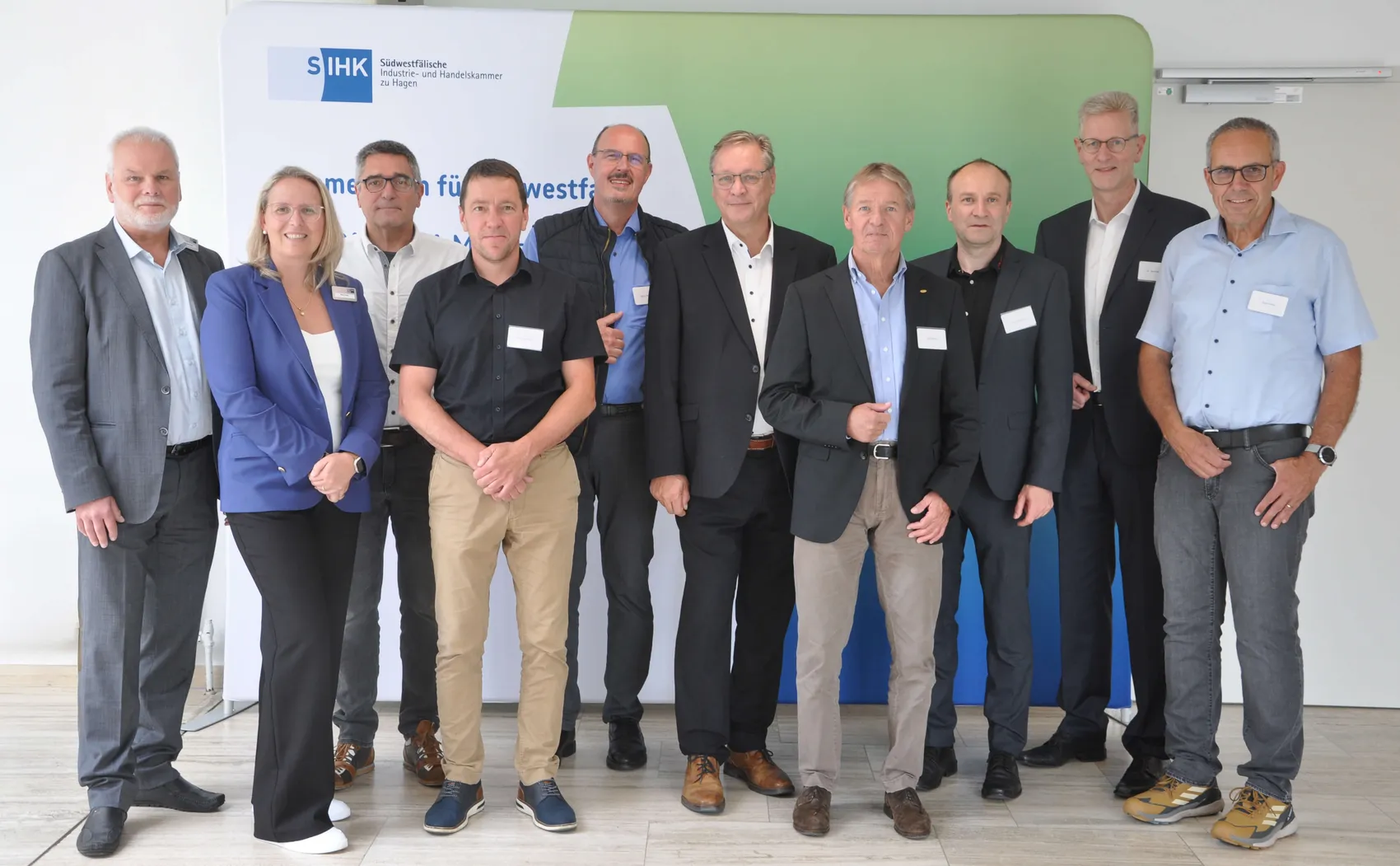 Eine Gruppe von zehn Personen posiert für ein Gruppenfoto vor einem Banner der Südwestfälischen Industrie- und Handelskammer.