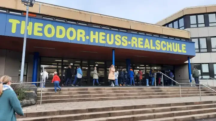 Das Gebäude der Theodor-Heuss-Realschule in Lüdenscheid mit einer Gruppe von Menschen vor dem Eingang.