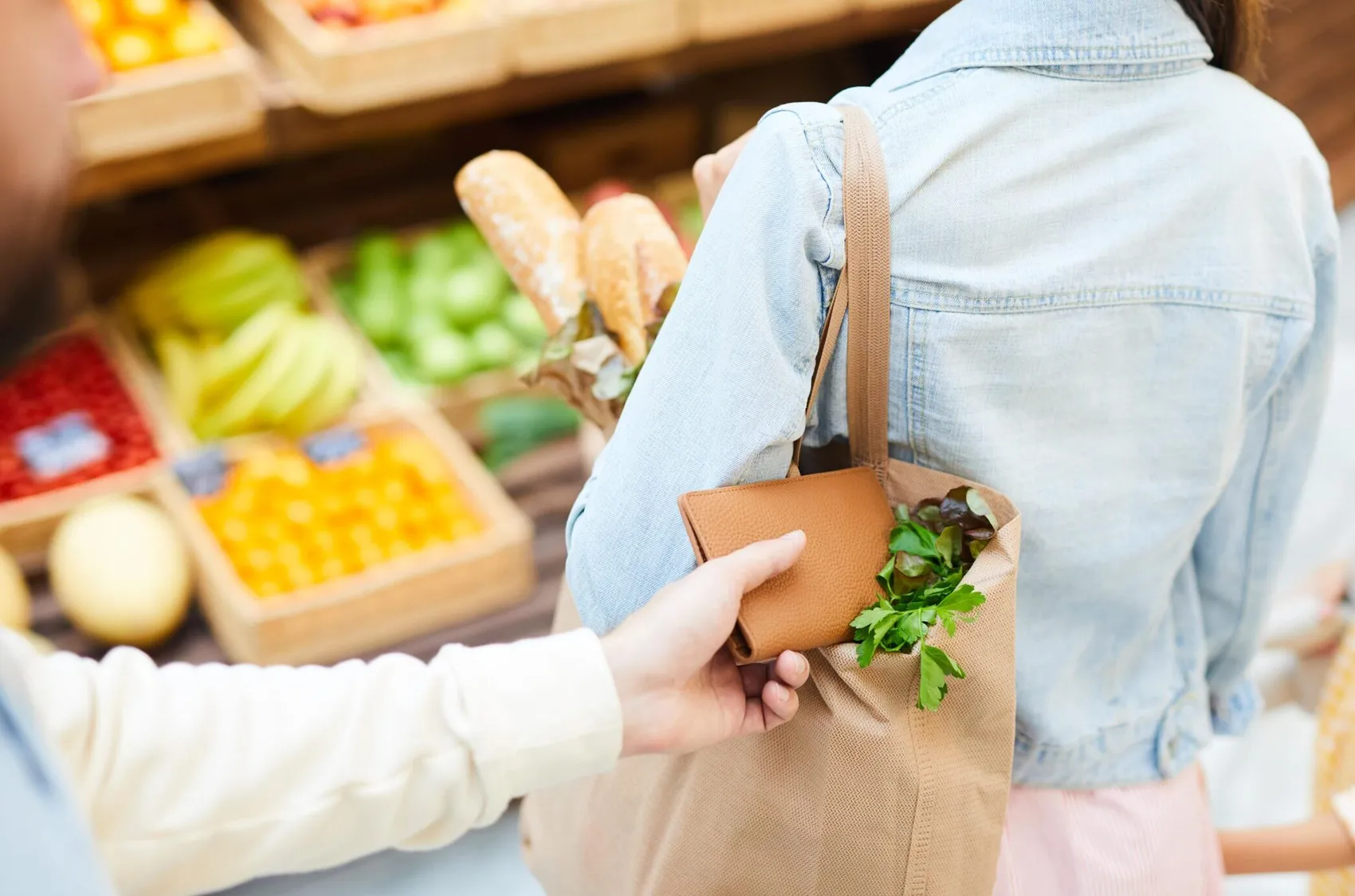 Eine Person versteckt eine Geldbörse in der Tasche einer anderen Person in einem Lebensmittelgeschäft.
