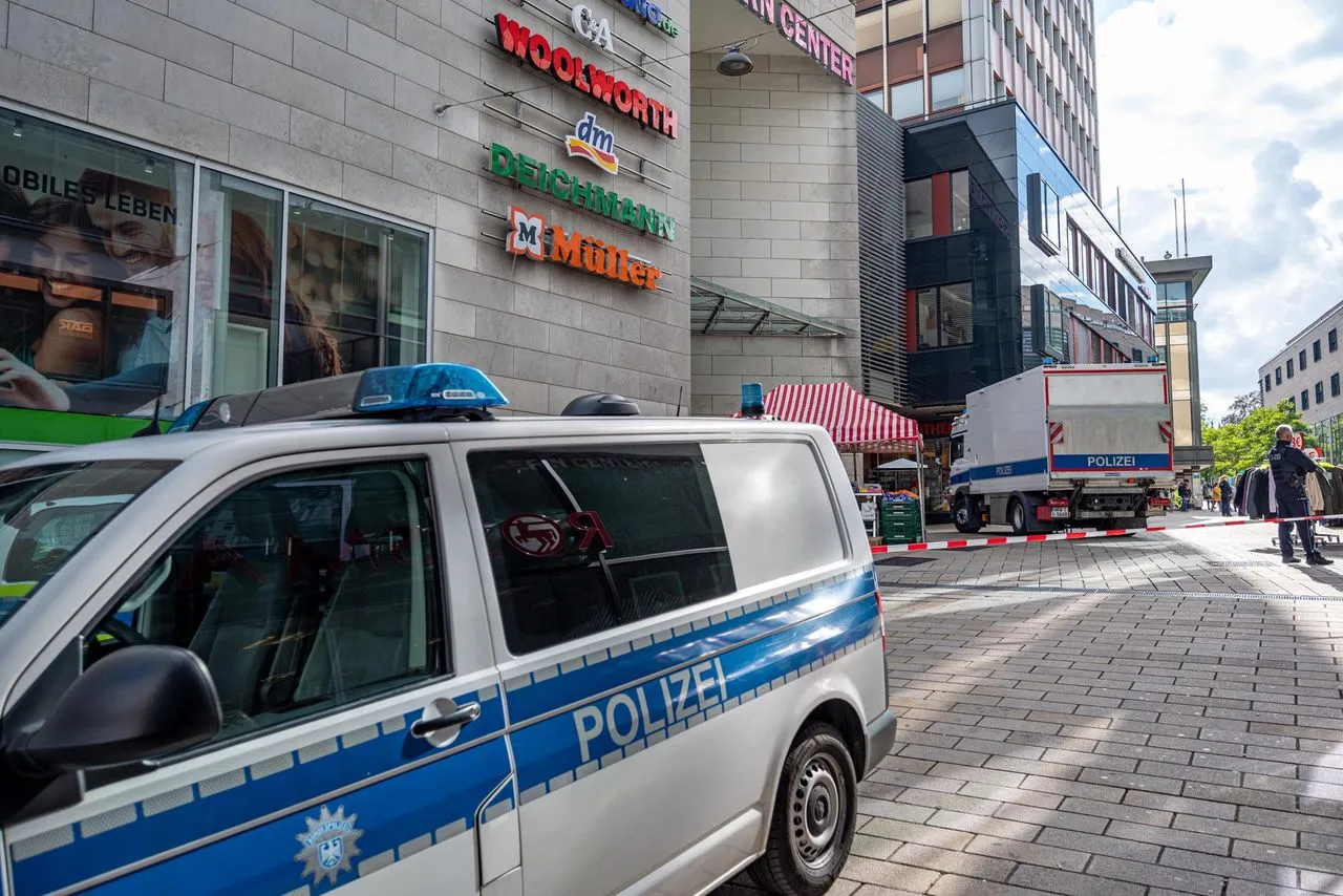 Polizeifahrzeuge blockieren eine Straße vor einem Einkaufszentrum mit Geschäften wie Woolworth, DM und Deichmann.