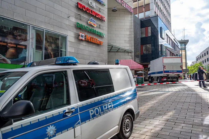Polizeifahrzeuge blockieren eine Straße vor einem Einkaufszentrum mit Geschäften wie Woolworth, DM und Deichmann.