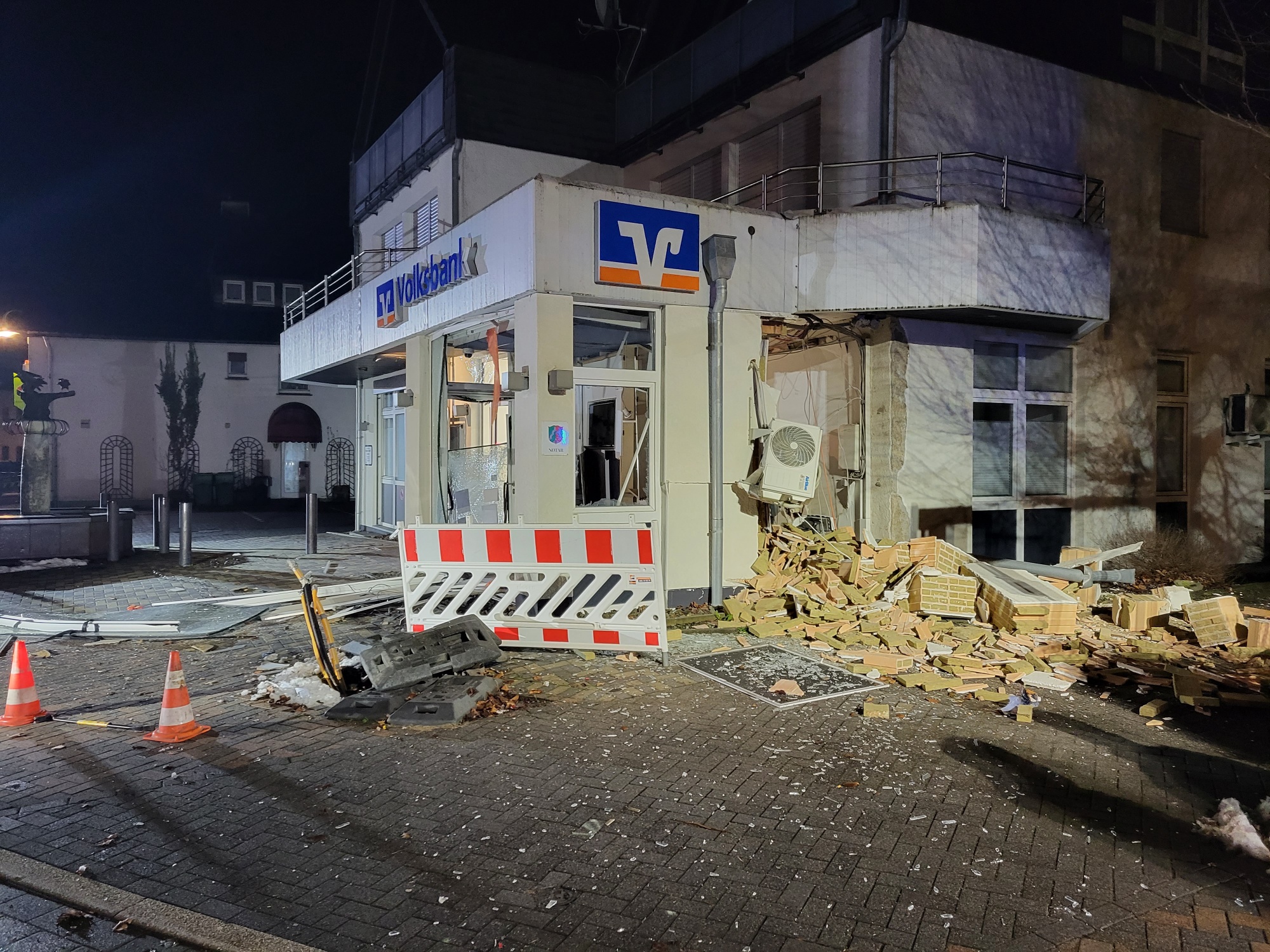 Beschädigte SB-Filiale der Volksbank Kierspe nach einem Überfall mit Sprengstoff, Trümmer vor dem Gebäude und Absperrungen.
