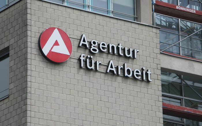 Das Logo der Agentur für Arbeit an einem Gebäude mit Fassade aus hellen Ziegelsteinen.