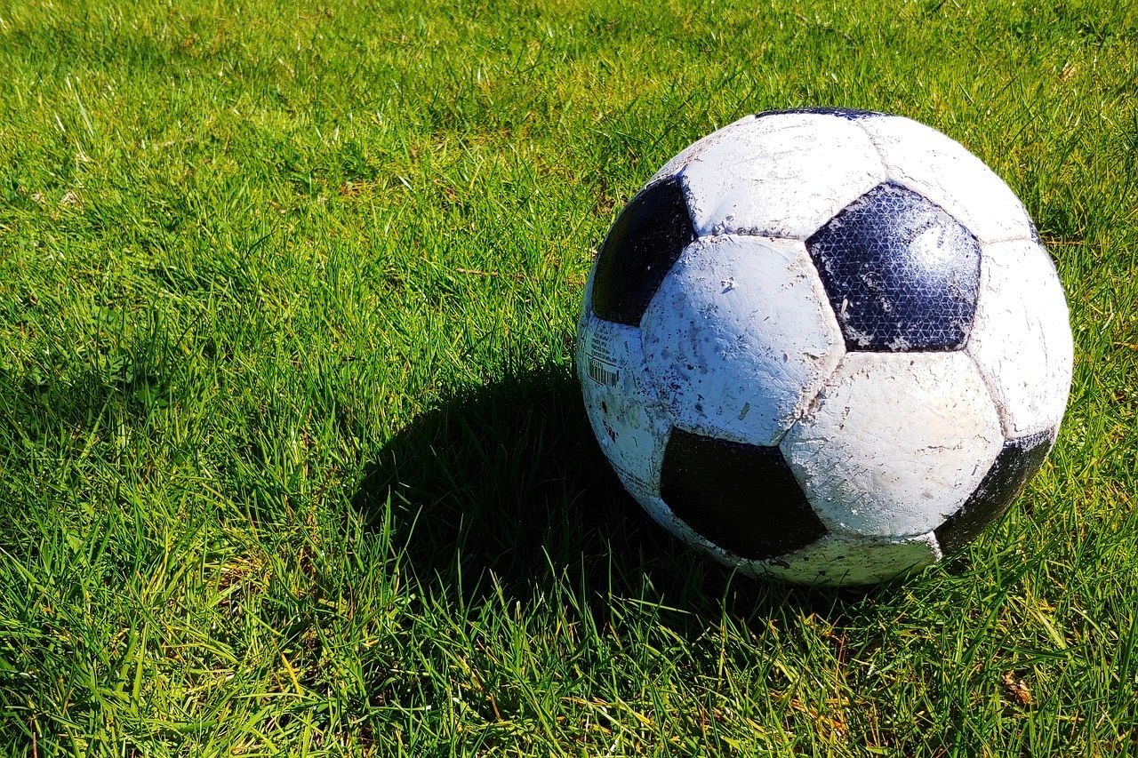 Ein schwarz-weißer Fußball liegt auf einer grünen Rasenfläche.