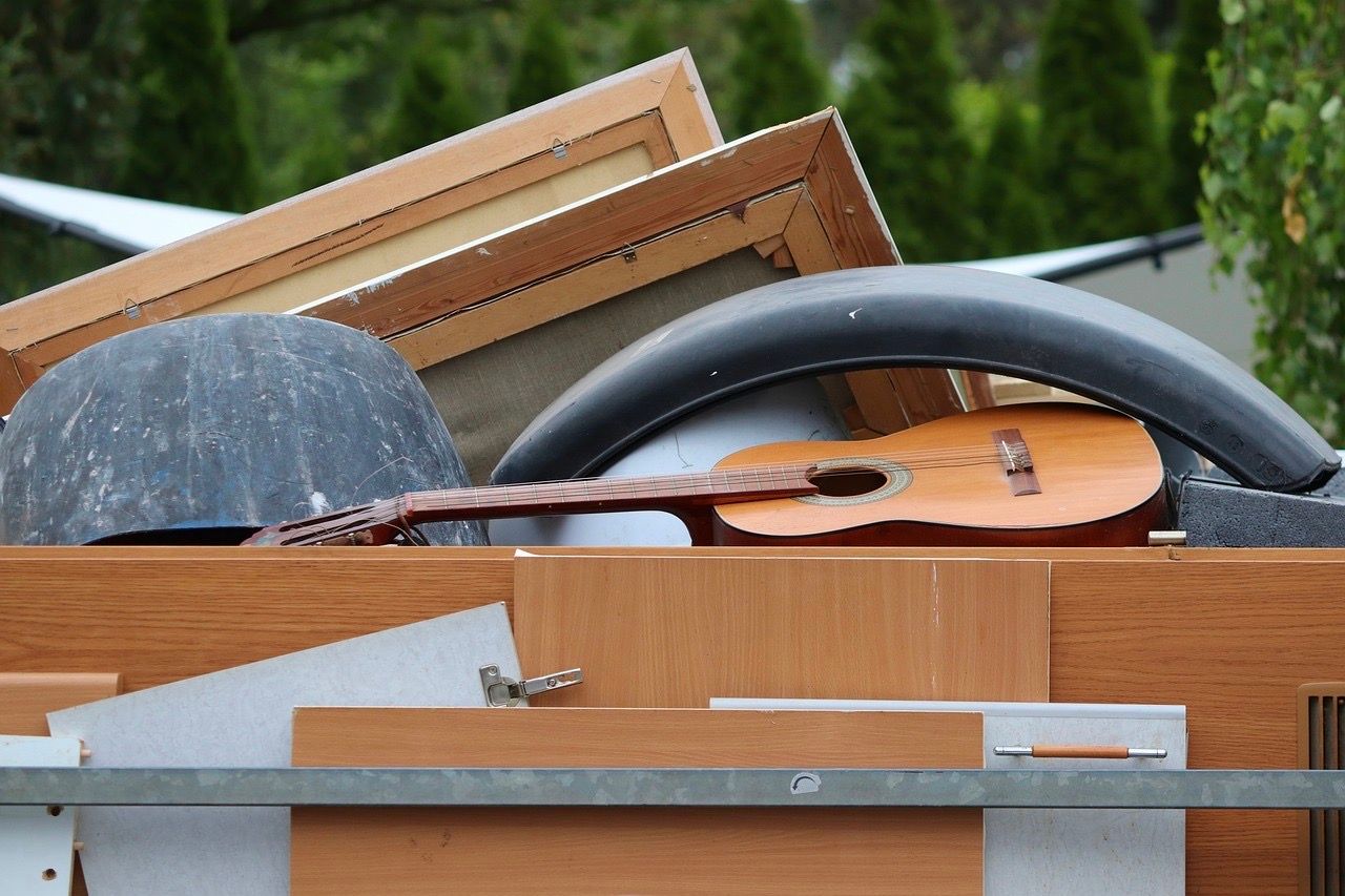 Verschiedener Sperrmüll wie ein Autoreifen, Gitarre, Bilderrahmen und Holzplatten stapeln sich übereinander.