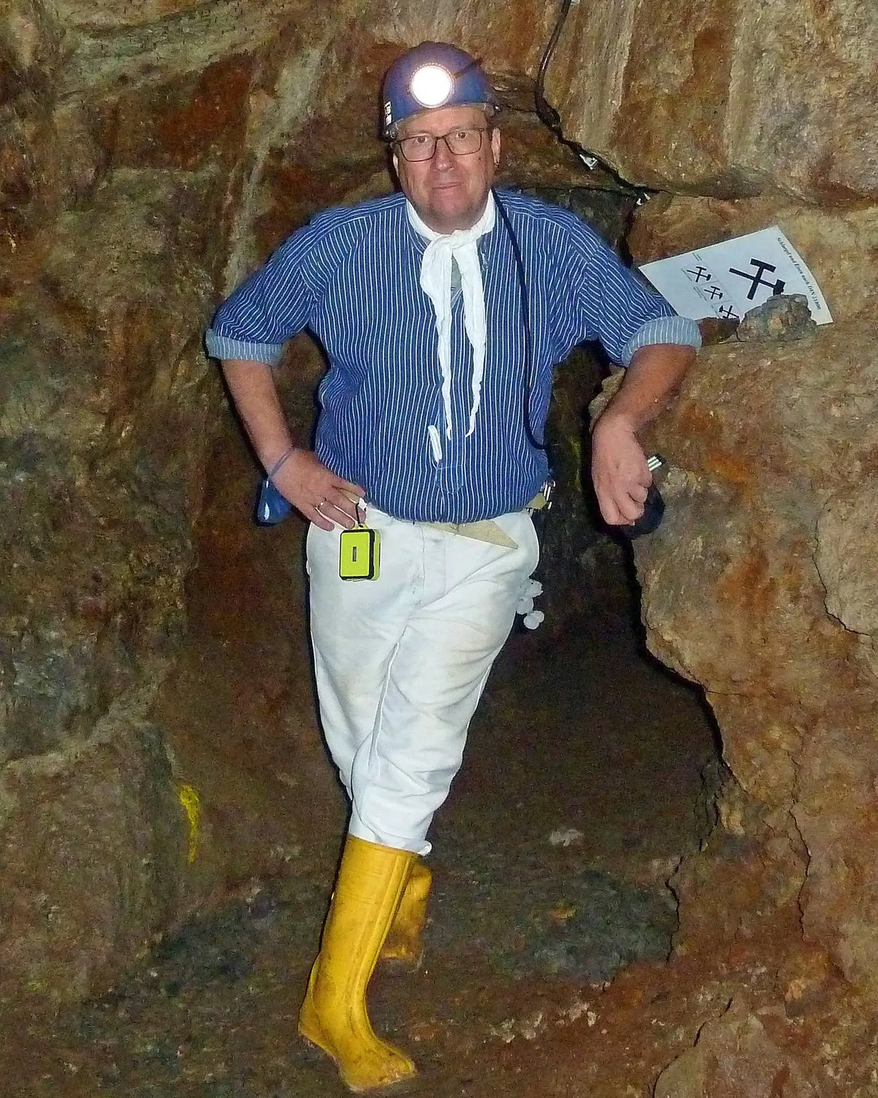 Mann in traditioneller Bergmannskleidung mit Helm und Stirnlampe steht in einem Stollen der Grube Neu Glück.