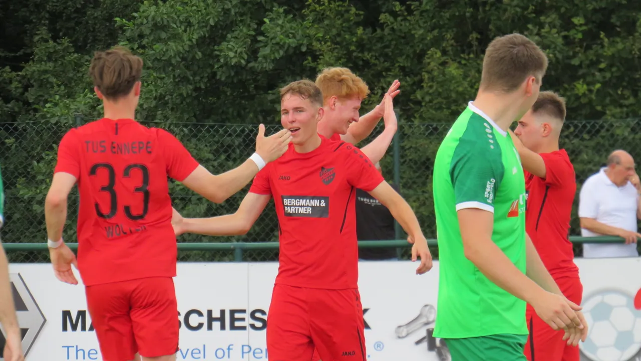 Spieler in roten und grünen Trikots jubeln und stoßen nach einem Tor zusammen.