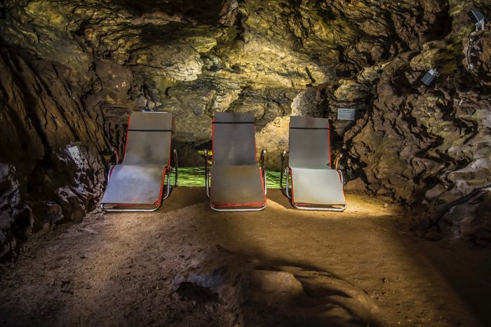 Drei Liegestühle stehen in einem beleuchteten Therapieraum innerhalb der felsigen Kluterthöhle.