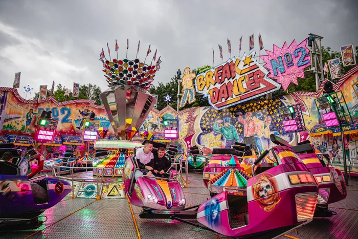Farbige Fahrgeschäfte des Break Dancer auf der Kirmes auf der Hohe Steinert in Lüdenscheid, mit Fahrgästen in den Autos.