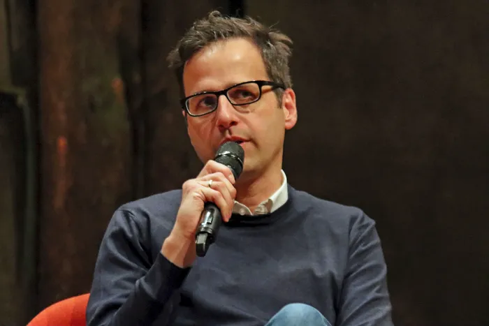 Lorenz Hemicker, Journalist und Buchautor, spricht in ein Mikrofon während einer Veranstaltung im EGM. Er trägt Brille und einen dunklen Pullover.