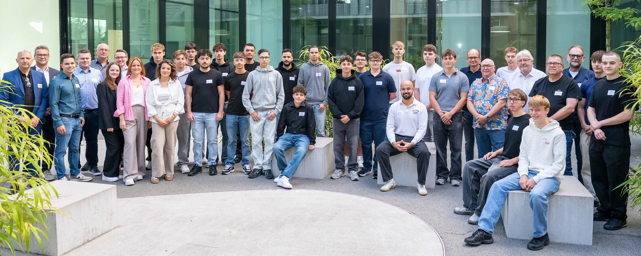 Eine Gruppe von Auszubildenden und Mitarbeitern der Enervie-Gruppe posiert für ein Gruppenfoto vor einem modernen Gebäude.