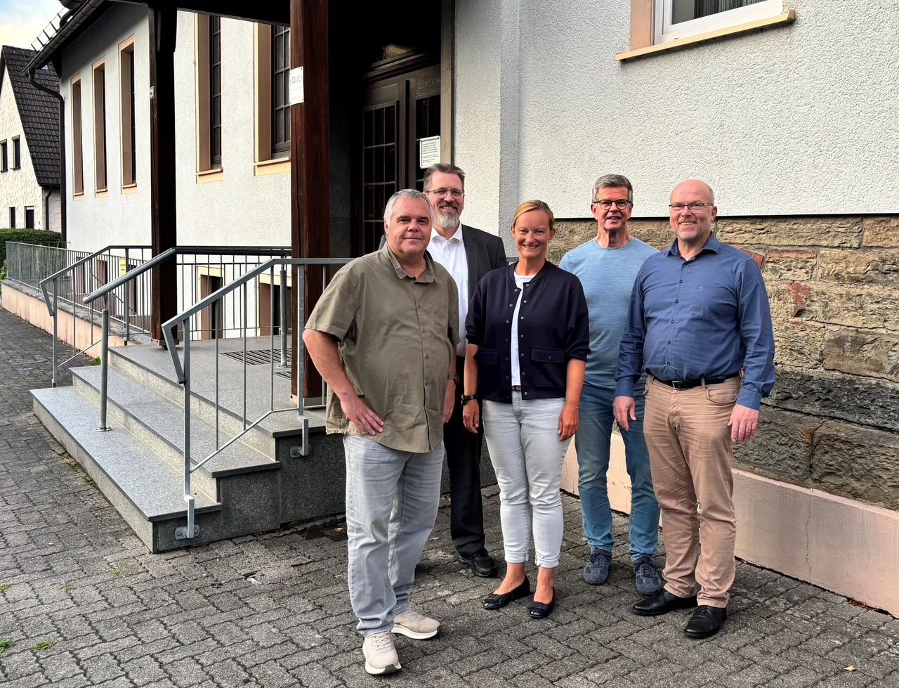 Die fünf Mitglieder der neuen Ohler Gemeindeleitung stehen nebeneinander vor einem hellen Gebäude mit Treppenaufgang.