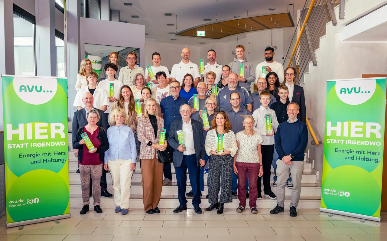 Eine große Gruppe von Menschen posiert auf einer Treppe und hält grüne Auszeichnungen.