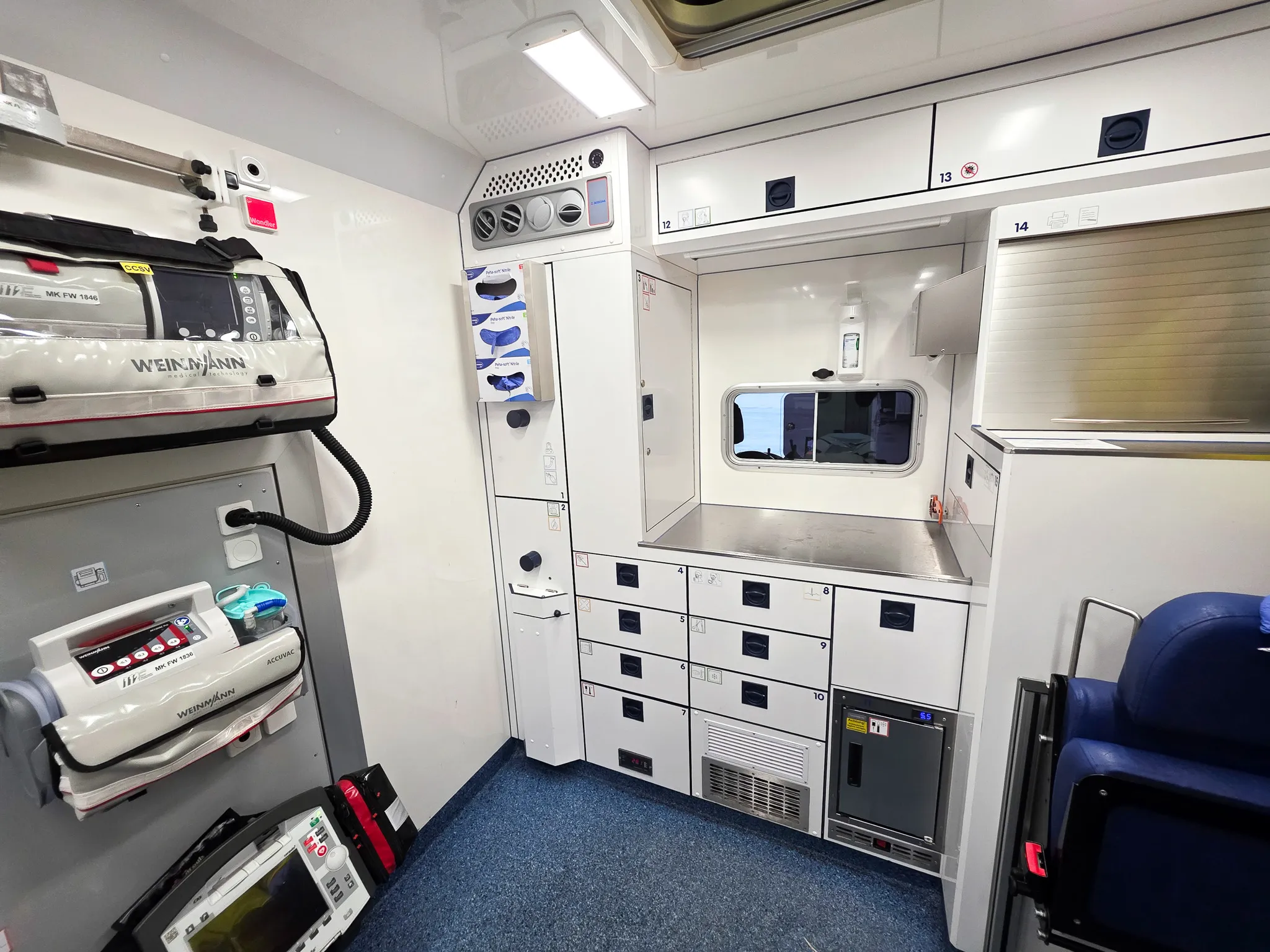 Innenraum eines Rettungswagens mit medizinischer Ausrüstung an der Wand und Schränken, bereit für den Transport eines Patienten ins Krankenhaus.