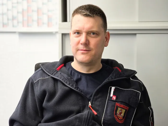 Christian Moll, Brandmeister und Notfallsanitäter der Feuerwehr Lüdenscheid, trägt eine dunkelblaue Uniform mit Abzeichen.
