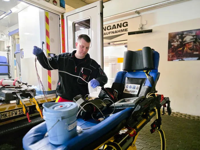 Ein Rettungssanitäter trägt Handschuhe und desinfiziert den Innenraum eines Rettungswagens nach einer Fahrt.