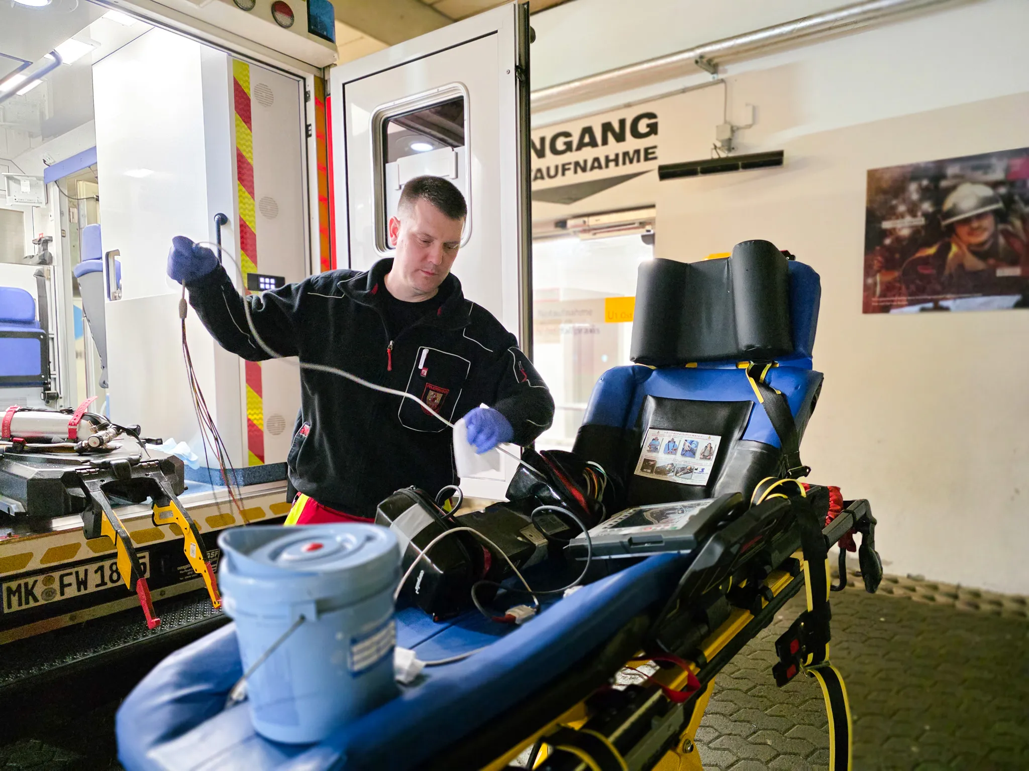 Ein Rettungssanitäter trägt Handschuhe und desinfiziert den Innenraum eines Rettungswagens nach einer Fahrt.