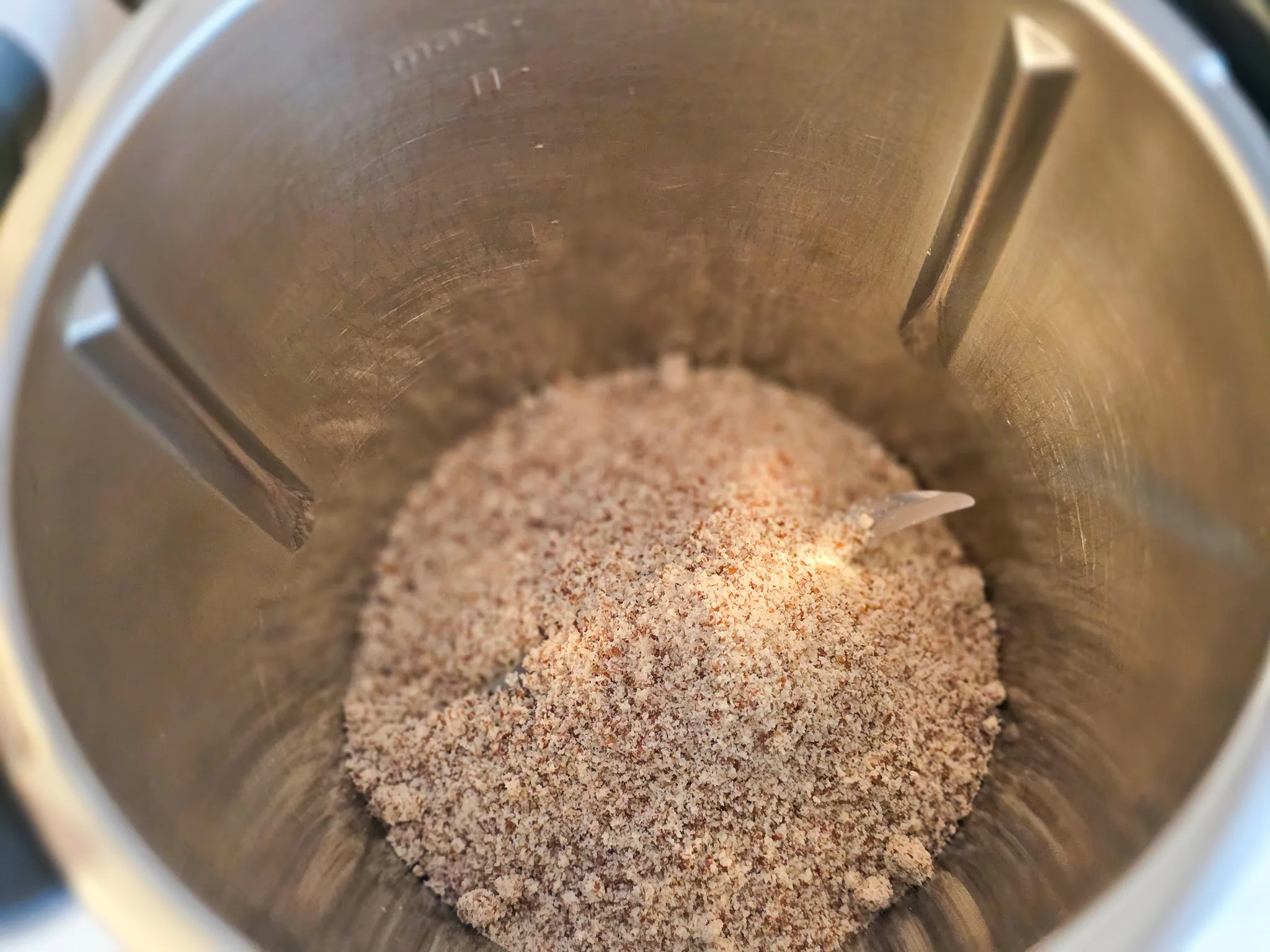 Gemahlene Mandeln füllen den Behälter eines Küchenmixers, vermutlich zur Herstellung von Rüblikuchen.