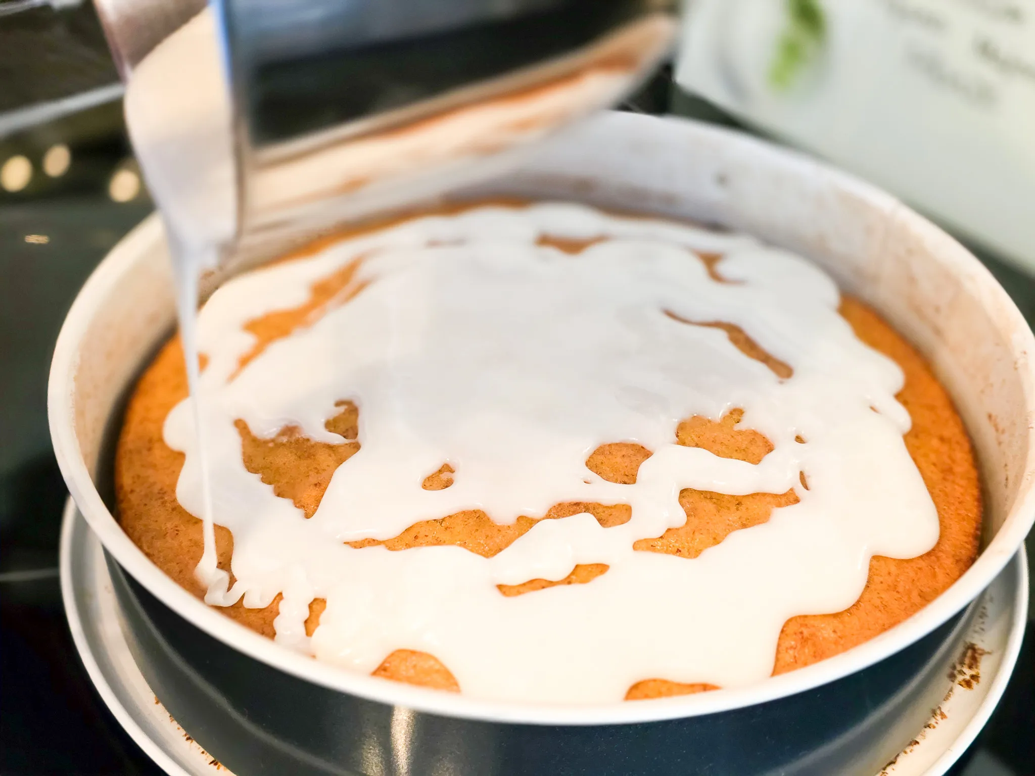 Ein Rüblikuchen in einer Springform wird mit weißem Guss übergossen.