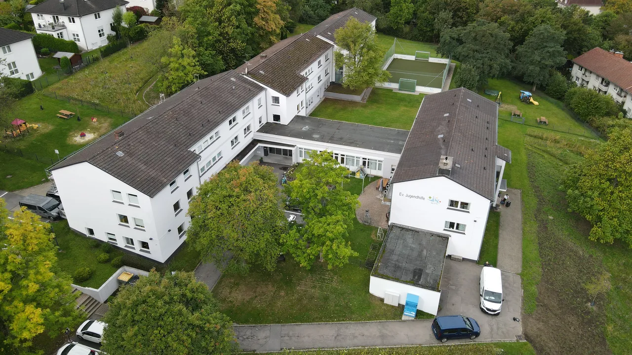 Luftaufnahme des Hauptsitzes der Evangelischen Jugendhilfe Iserlohn-Hagen, ein mehrflügeliger Gebäudekomplex mit gepflegtem Gelände und Parkplätzen.