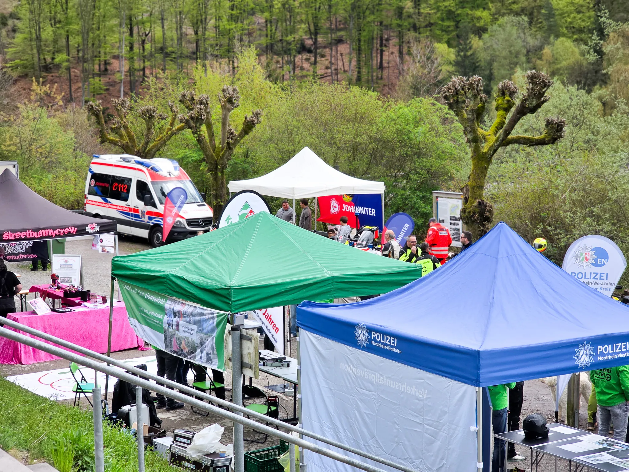 Mehrere Zelte der Polizei und des Johanniter-Unfallhilfsverbands stehen an einem Hang, im Hintergrund ein Rettungswagen und Bäume. Die Veranstaltung dient der Prävention für Motorradfahrer.