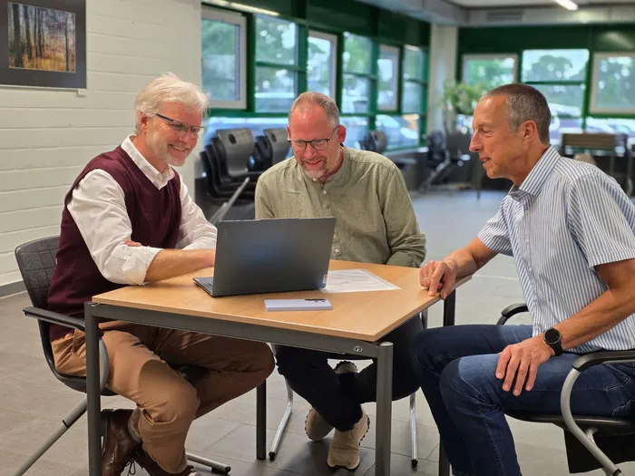 Drei Männer sitzen an einem Tisch und betrachten ein offenes Laptop. Von links sind Claus Peter Wirth, Armin Kibbert und Peter Hasz zu sehen.