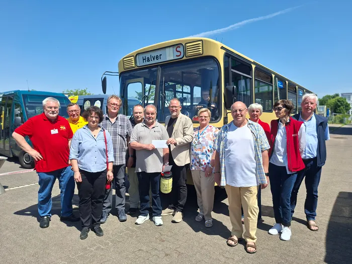 Eine Gruppe von etwa zehn Personen steht vor einem gelben Bürgerbus mit dem Zielort 