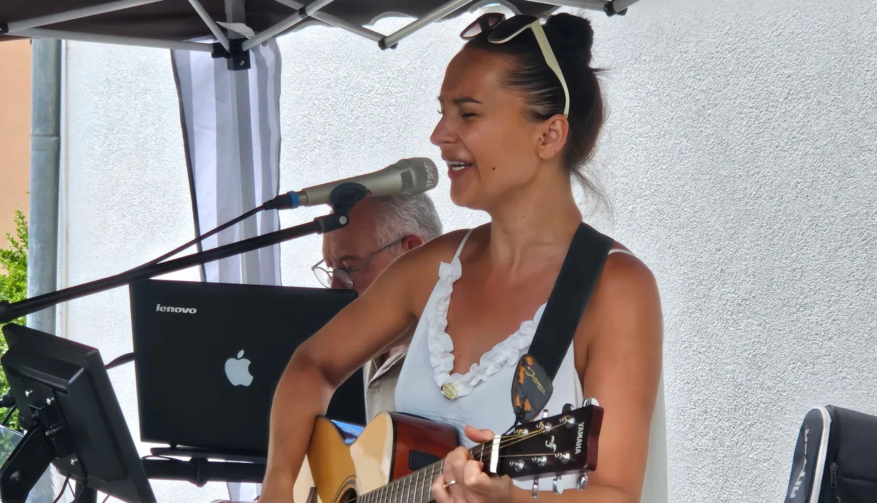 Kathy Böcker vom Duo „SubsTanz“ spielt Gitarre und singt in ein Mikrofon.