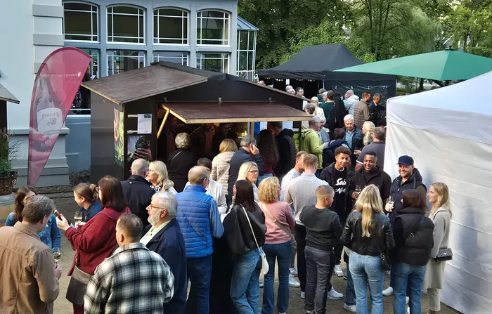 Menschenmenge vor einem hölzernen Verkaufsstand auf dem Weinfest im Volmepark.